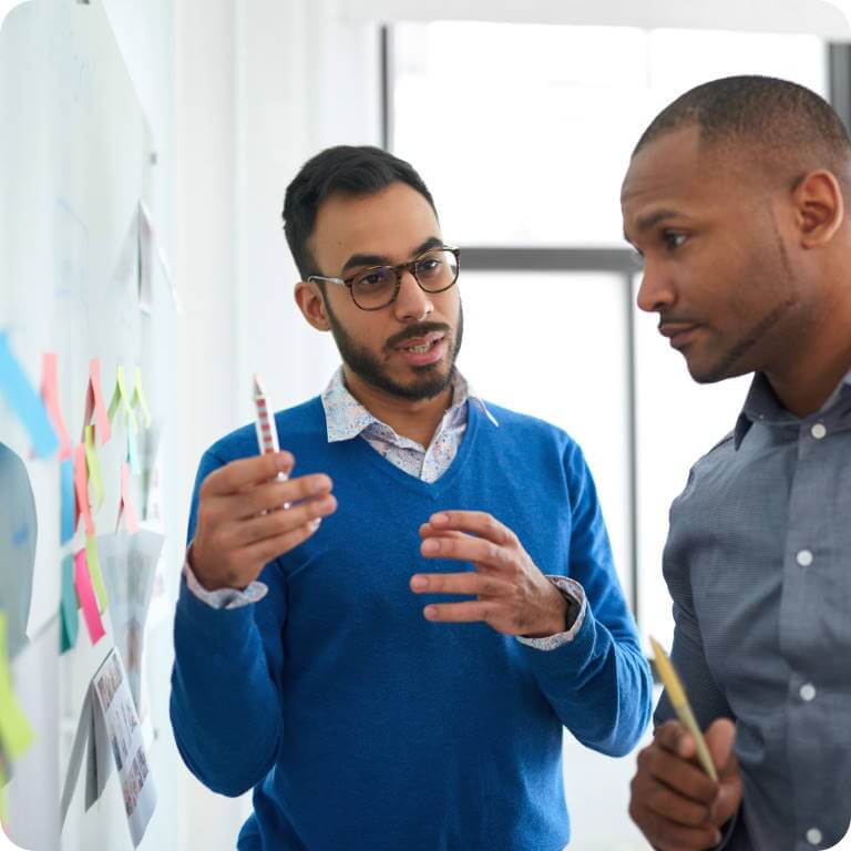 Coworkers in front of a whiteboard having a discussion