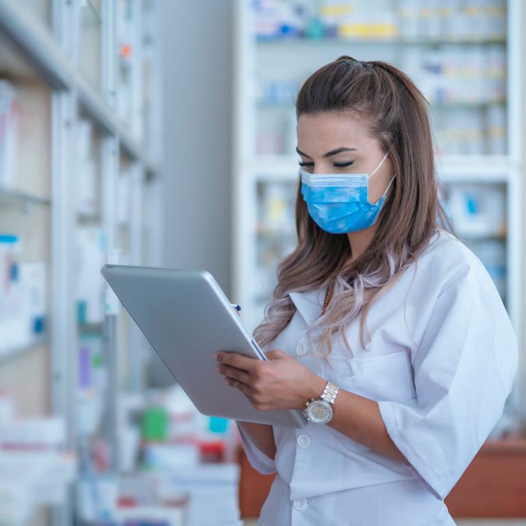 Masked pharmacist working on a tablet