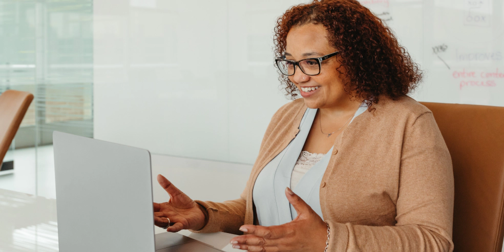 A smiling woman looking at her laptop.