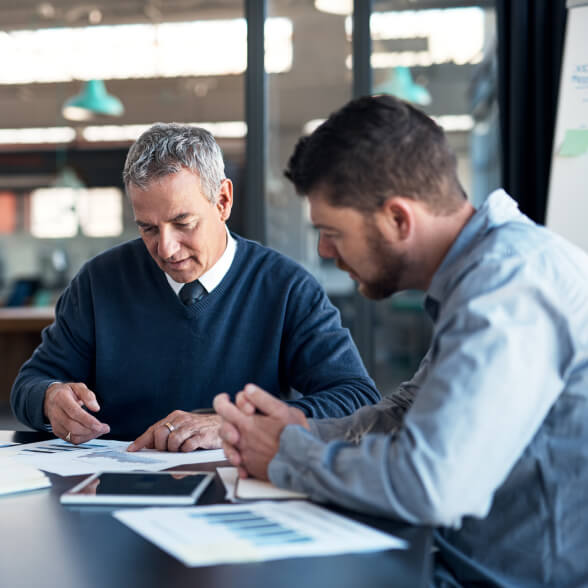 Two seated people looking over some documents.