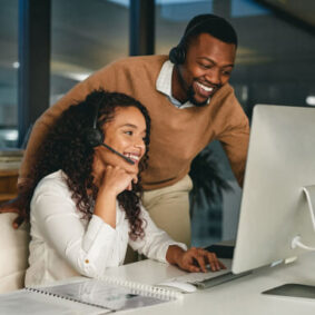 Smiling co-workers look at monitor.