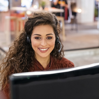 A smiling woman looking at her computer monitor.