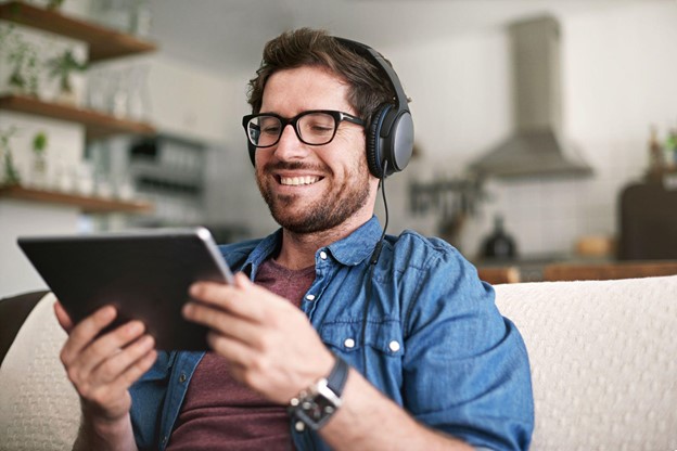 A man wearing headphones looks at a tablet screen