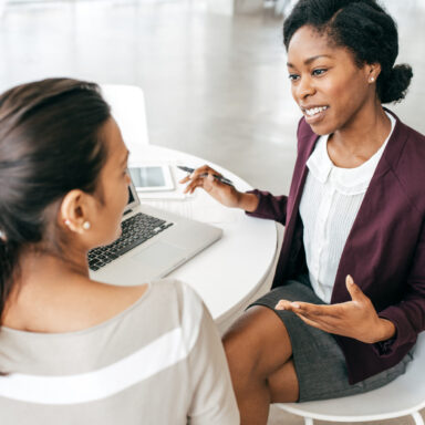 Two women seated at a desk in conversation