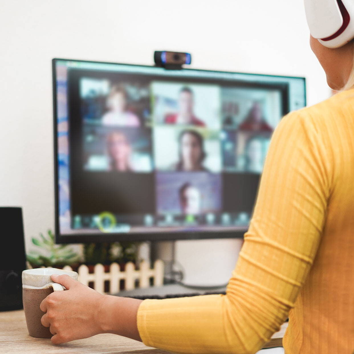 Woman seated in front of her computer monitor and wearing headphones.