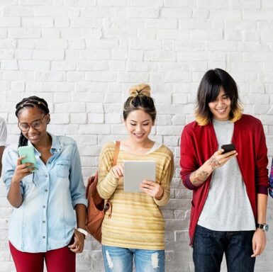 A group of smiling people looking at their mobile devices.