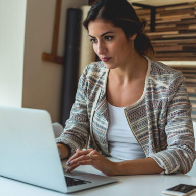 A woman seated at a desk working on a laptop.