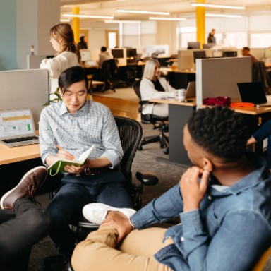 Two people seated at workstations in conversation.