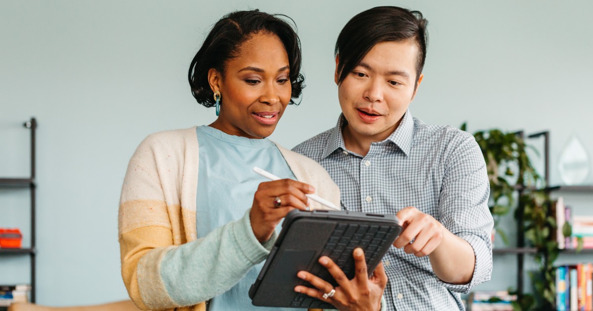 Two people looking intently at a tablet.