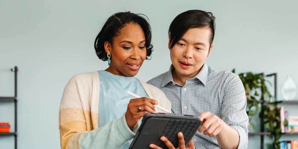 Two people looking a notepad.