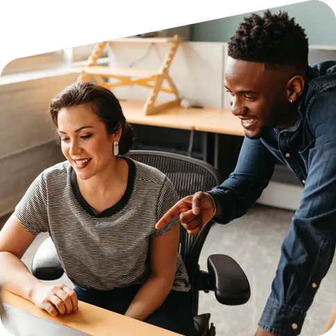 Two smiling workers looking at a laptop screen.