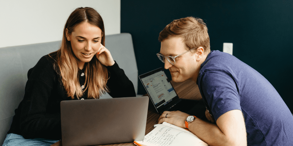 Two people looking at laptop screen.