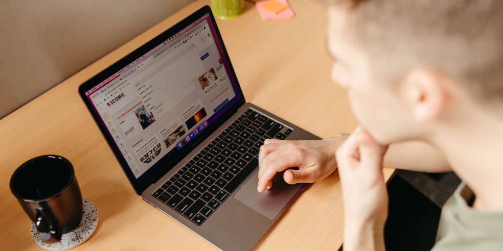 A man looking at computer and scrolling through a webpage.