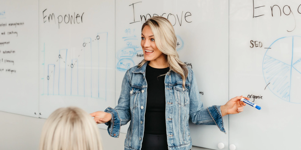 A person standing at a dry erase board delivering sales training